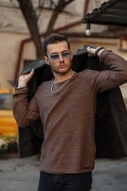 Man wearing sunglasses putting on a jacket