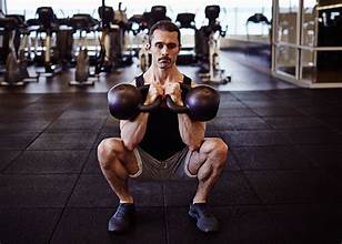 workout benefits Man doing squats with bells