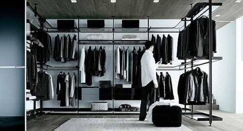 Man in his closet viewing his clothes Men's Wardrobe Essentials