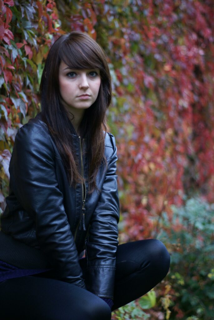 perfect leather jacket  girl wearing jacket in front of changin leaves