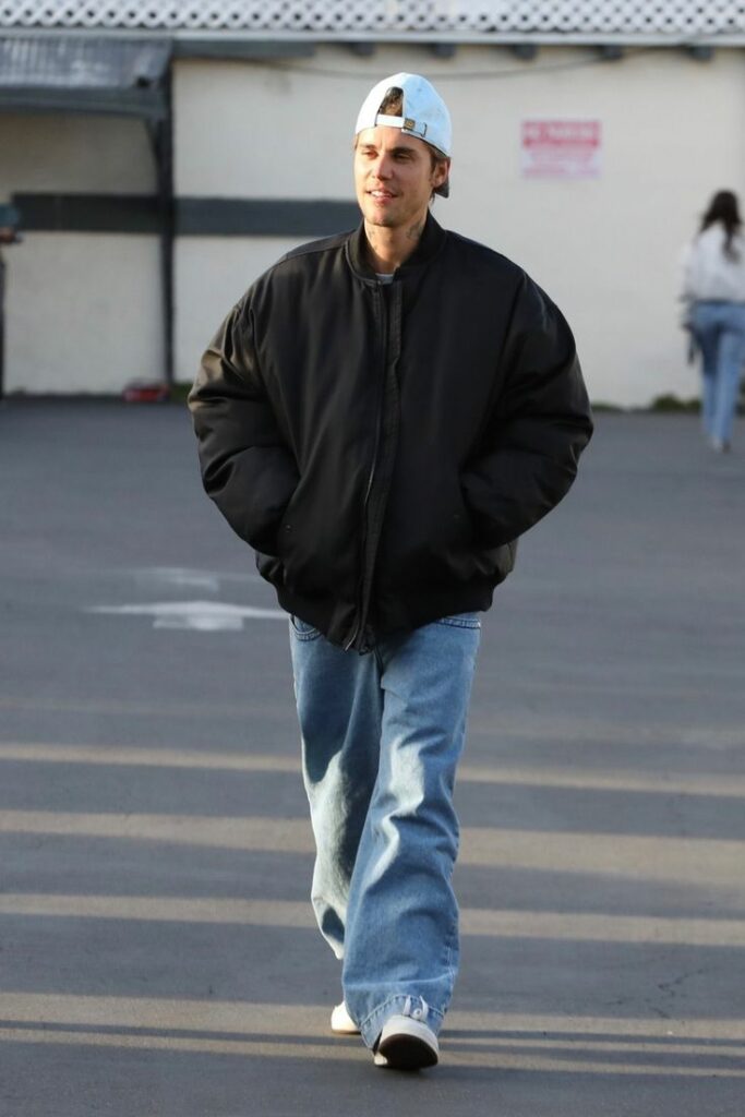 Man in black bomber jacket with white baseball cap 