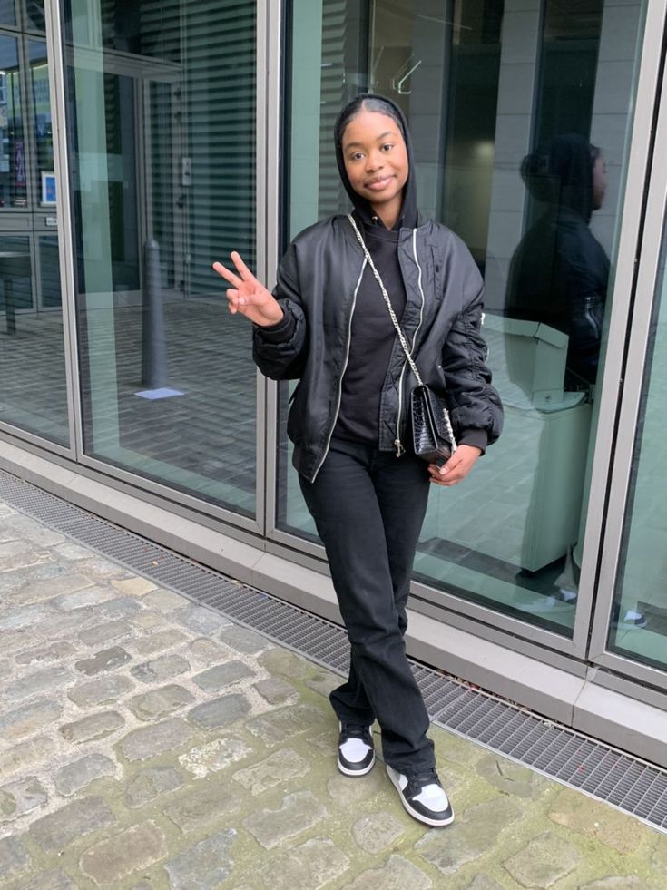 Girl in black bomber jacket giving peace sign 