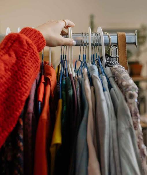 Fast Fashion and Slow Fashion clothes on a rack with hand 