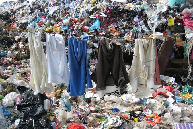 Fast Fashion and Slow Fashion clothes hanging in a dump