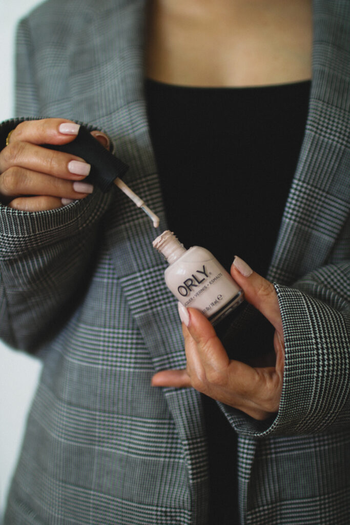 holding as bottle of pink Orly Nail Polish