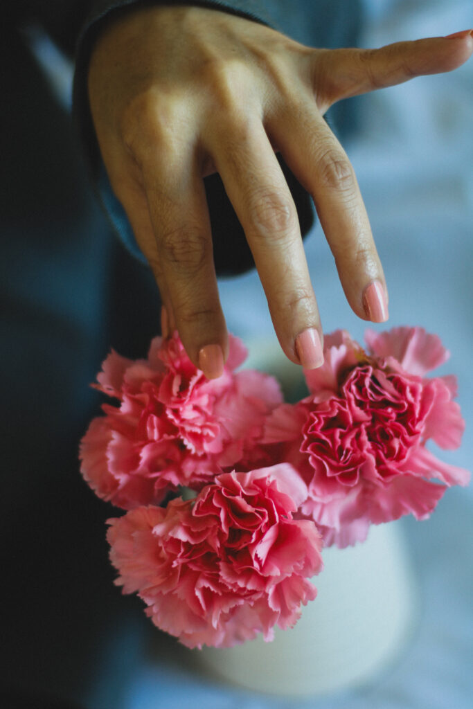 nails in light pink Orly Nail Polish touching flower