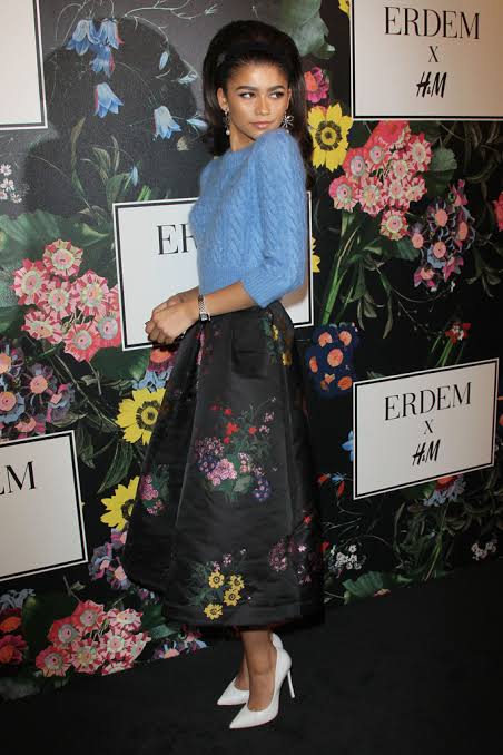 global influences on fashion celebrity in blue sweater and floral pring skirt
