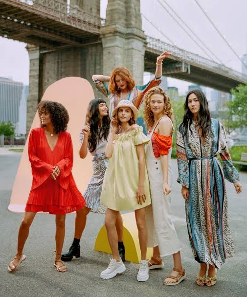 global influences on fashion brightly dressed models in front of bridge