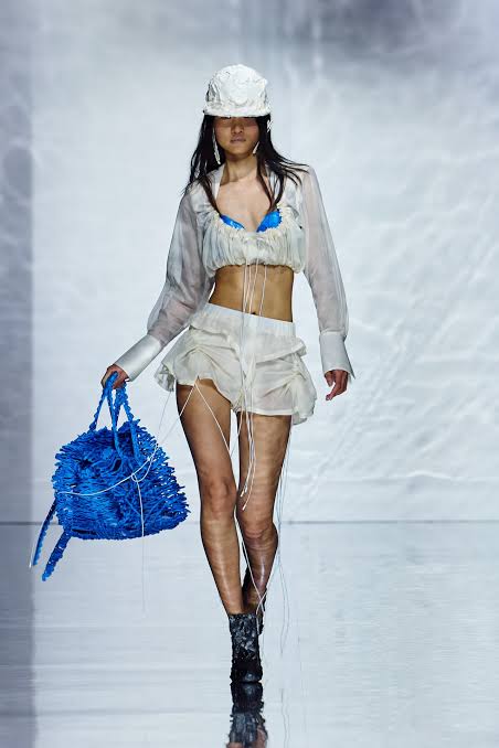 runway model in skimpy white outfit with hat 