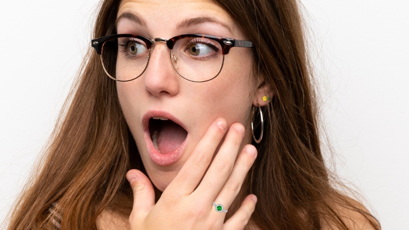 woman in glasses wearing an emerald and diamond ring