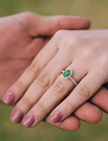 holding hands wearing emerald and diamond ring