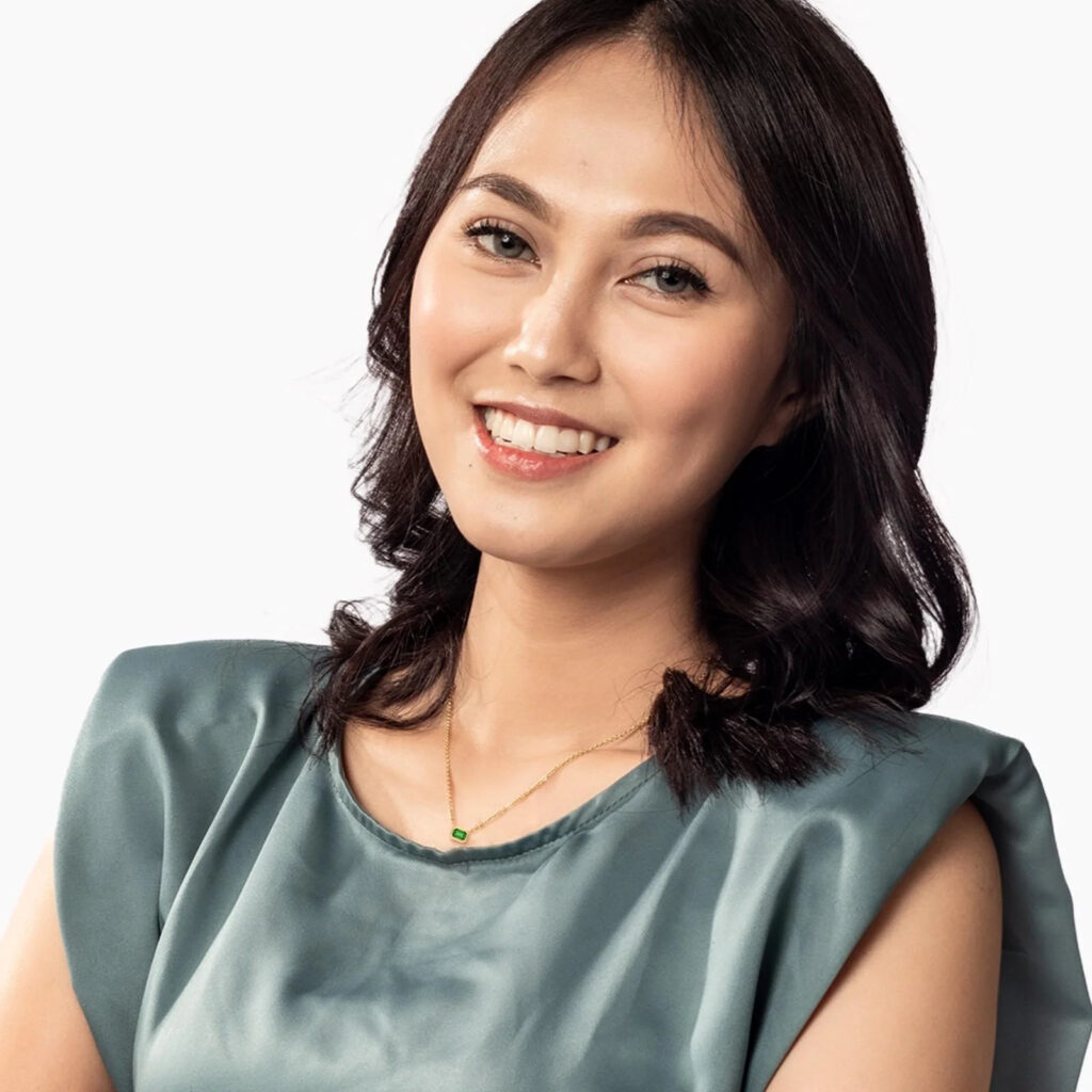Woman in green top wearing emerald and diamond jewellery