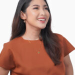 woman in orange top wearing emerald and diamond jewellery