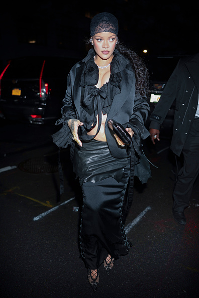 Rihanna donned an Ann Demeulemeester maternity costume to the 2025 Met Gala After-Party, which featured a satin jacket layered with a jacquard silk blouse and a lace-up maxi skirt in fluid cady with a raw-edge leather apron.