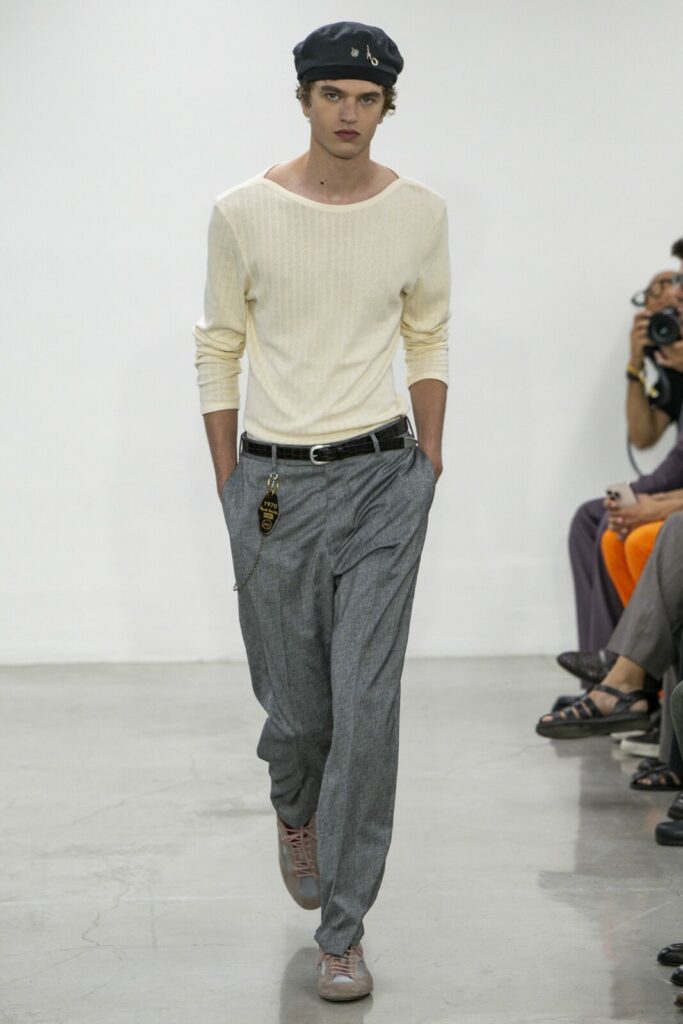 Male model in white knit top and grey pants on the runway at Milan Fashion Week