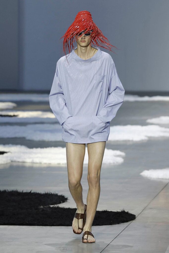 Male model in pinstripe shirt and red straw style hat on the runway at Milan Fashion Week