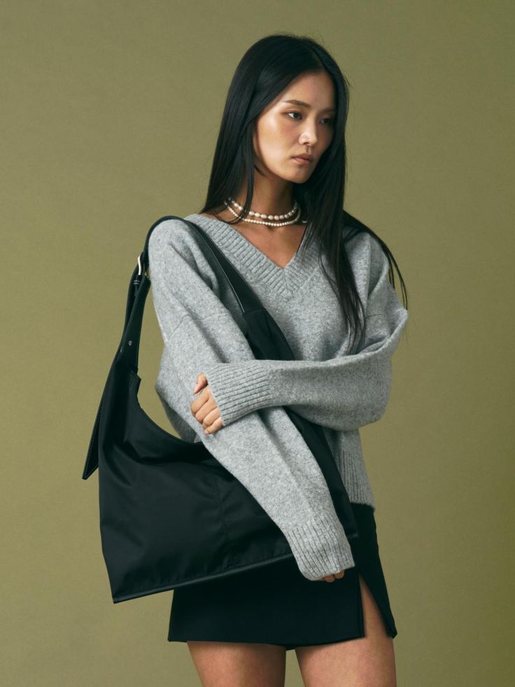 Woman wearing gray sweater and black skirt with black nylon bags