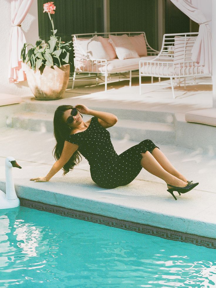 woman sitting by pool wearing matching sirt and black and white Polka dot capri pants