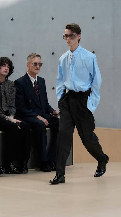 Model wearing glasses blue dress shirt and navy pants at Paris Fashion Week Men’s