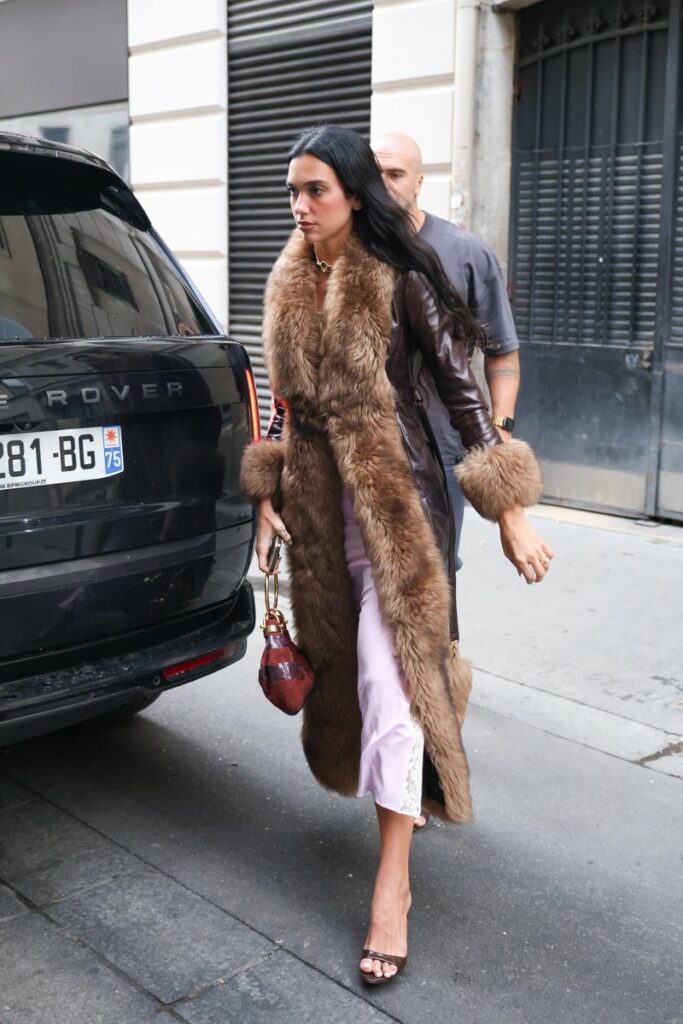Dua Lipa attends Paris Fashion Week Haute Couture Fall/Winter 2025/2026 in a Chloé Long Column Coat and Creamy Lilac Spaghetti Strap Midi Dress