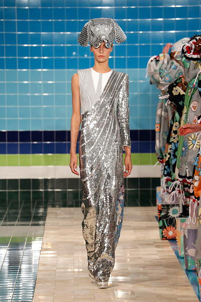 A fashion model walks the catwalk for Thom Browne’s Spring/Summer 2017 collection in a silver one-shoulder sequin dress.