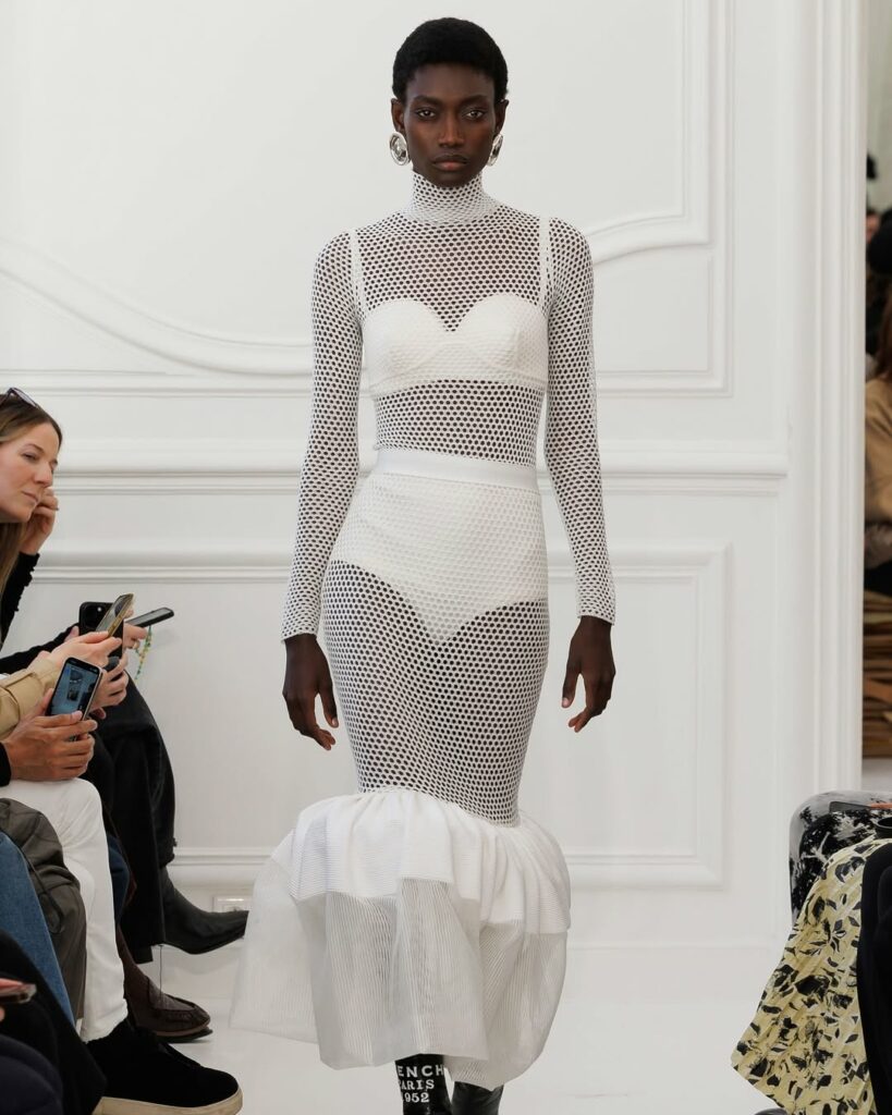 Fatou Kebbeh walks the runway during Sarah Burton’s Givenchy Fall/Winter 2025 show, modeling a white fishnet outfit.