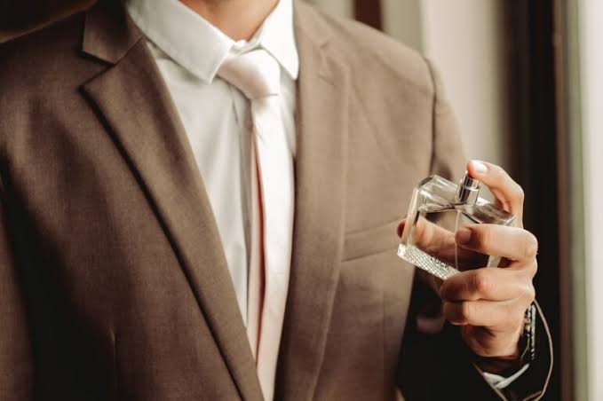 man in suit holding mens perfume 