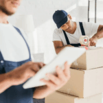 Man looking at list while other man packs box