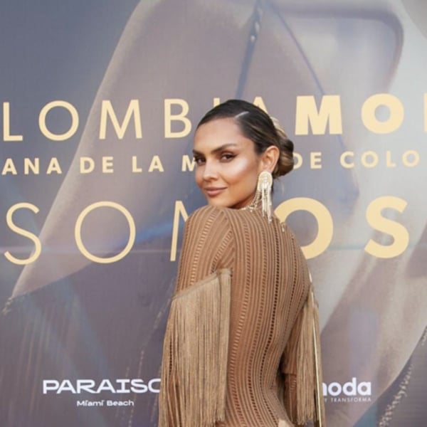 Model wearing long dress in front of promotional sign at Colombia Fashion Week 