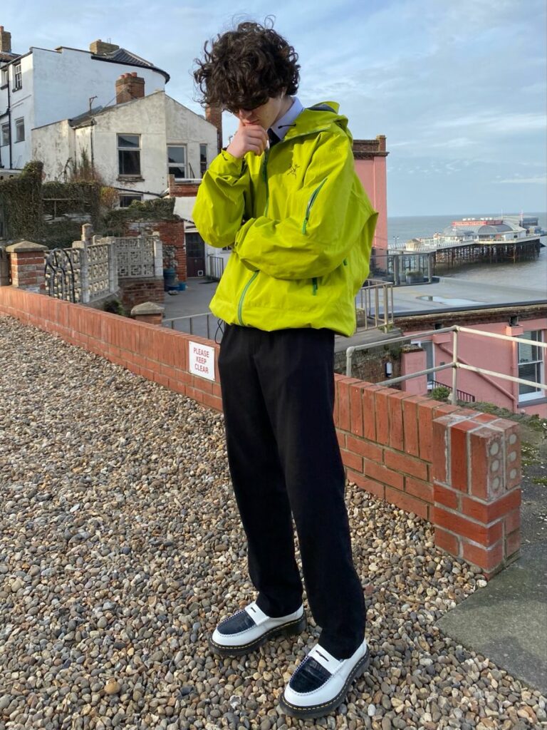 Young man with long hair wearing green windbreaker
