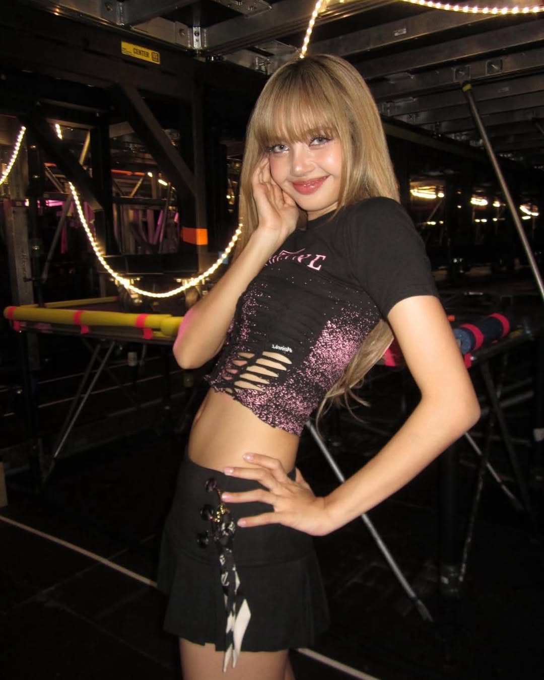 Blackpink Lisa dressed stunningly in a black short-sleeve tee printed with the “Blackpink Deadline Tour” insignia and odd cutouts down the hem.