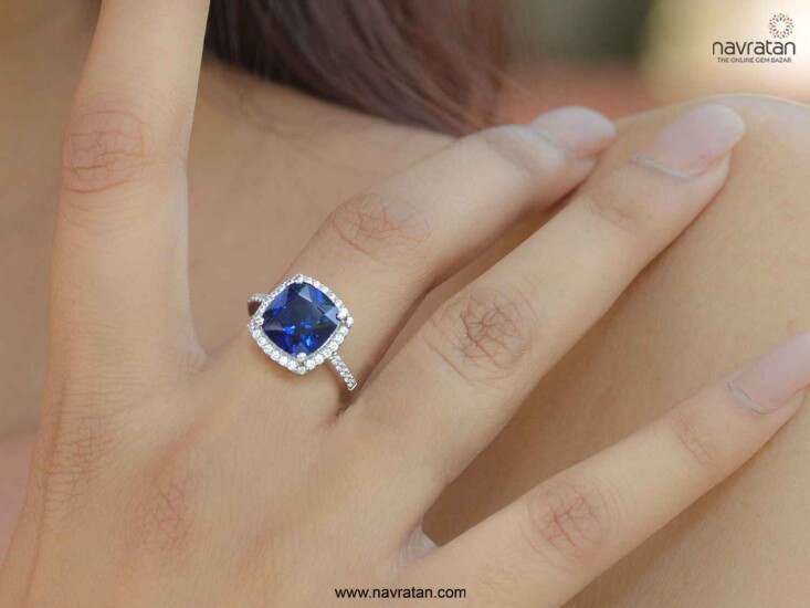 finger with ring bearing blue sapphire stone