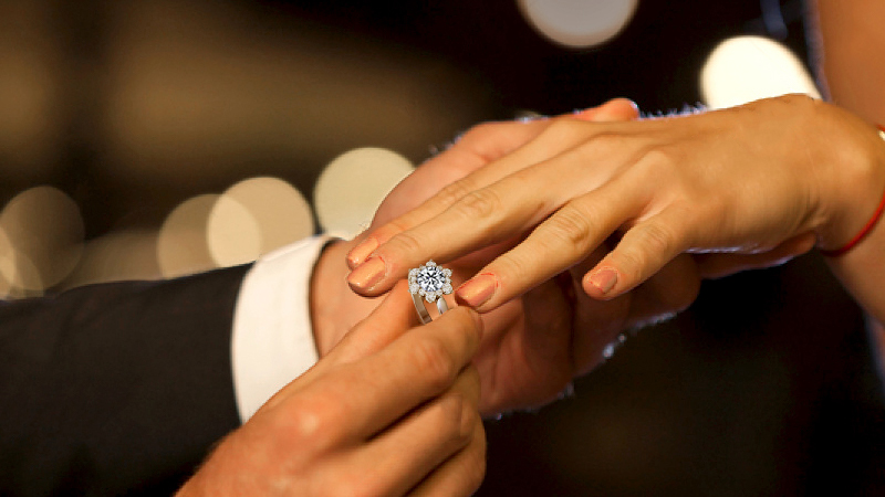 hand putting diamond ring on a finger