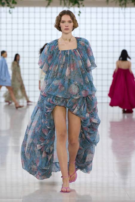 Model in blue open front dress on runway 