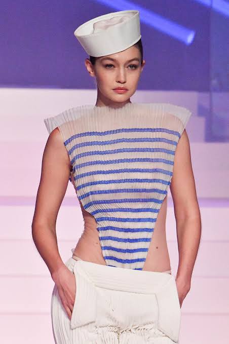 Runway model wearing sheer white with blue stripes body suit 