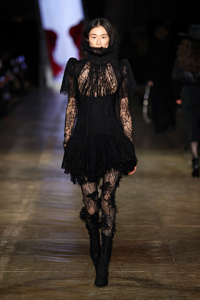 Chu Wong walks the runway during the Alexander McQueen Fall/Winter 2025/2026 collection show at Paris Fashion Week, dressed in a black embroidered Chantilly lace dress.