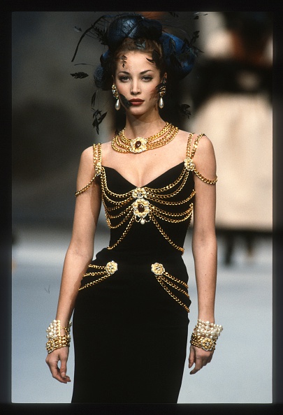 Christy Turlington walks the runway for Chanel Haute Couture’s Spring/Summer 1992/1993 collection presentation, wearing a black dress studded with gold chain links