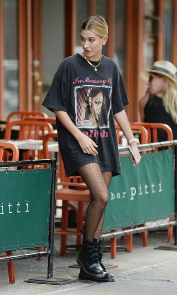 Girl wearing oversized graphic Tee as a dress with fish net stockings