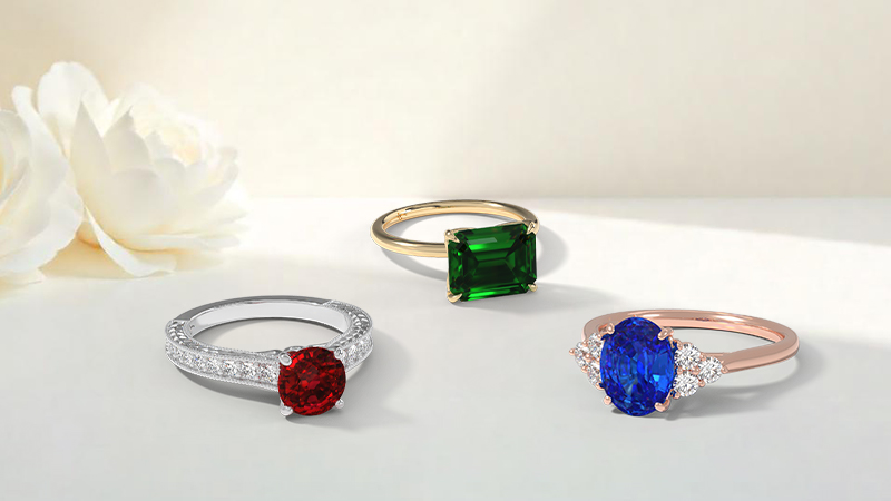 3 rings one with red stone, one blue and one green to show the evolution of engagement rings