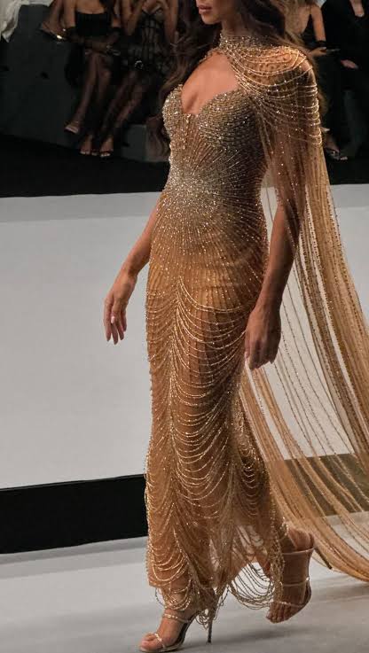 Model wearing gold dress on the runway 