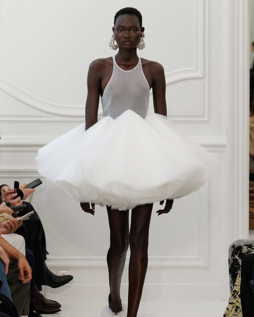 Model on the runway wearing the same white dress Ariana Grande wore at the VMA's