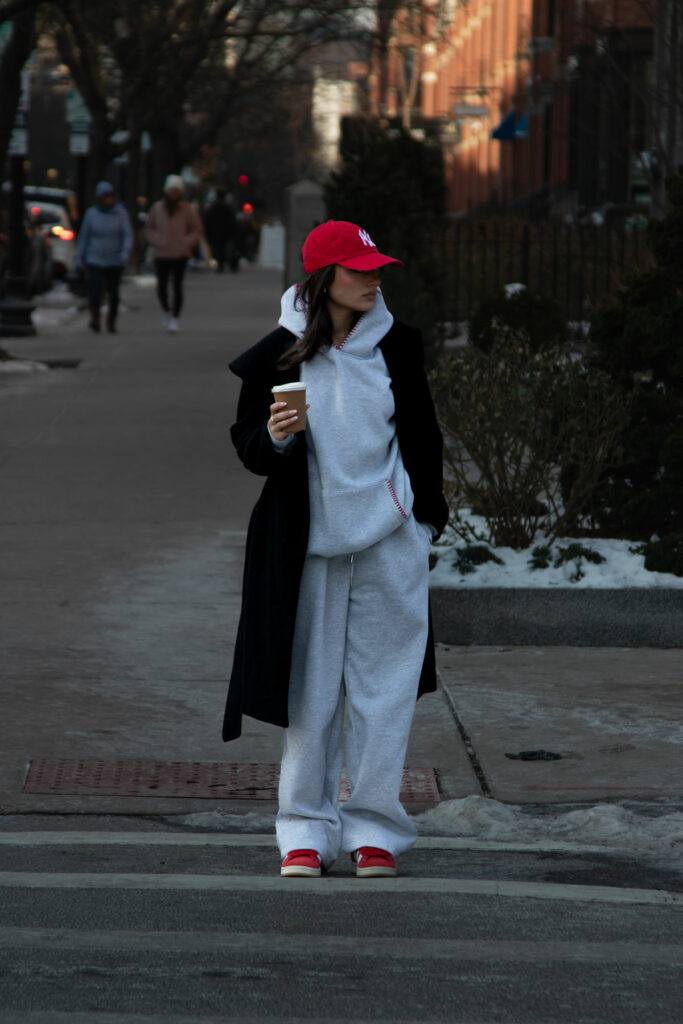 Girl wearing a long dark coat, and gray swaets