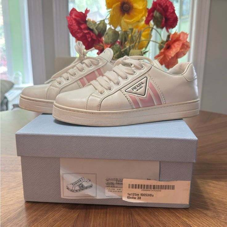 pair of Prada sneakers for women on top of shoe box and in front of flowers
