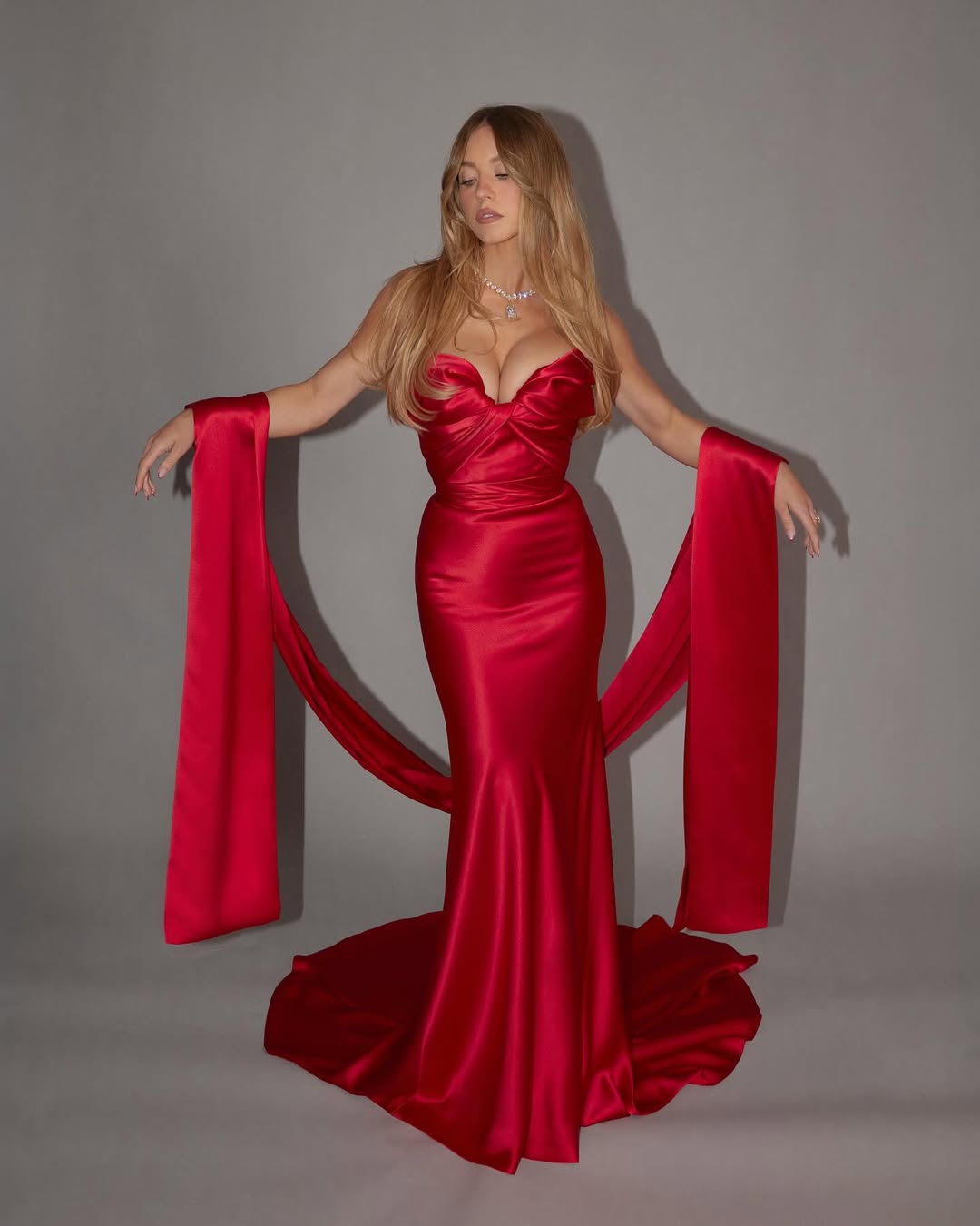 Sydney Sweeney in a custom Oscar de la Renta scarlet red satin gown with a matching satin scarf at the 77th Primetime Emmy Awards.