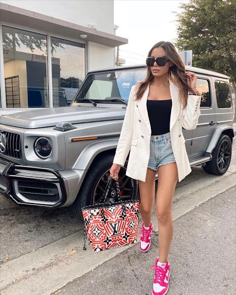 Woam in a white blazer, black tube top, shorts and Nike sneakers 