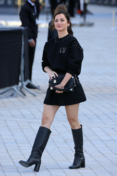 Anna de Armas attends the Louis Vuitton Womenswear Spring/Summer 2026 presentation at the Louvre during Paris Fashion Week, dressed in a sweater and an A-line skirt.
