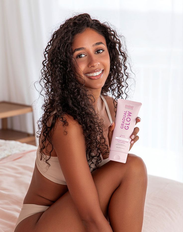 tanned girl holding tube of gradual tanning Lotion