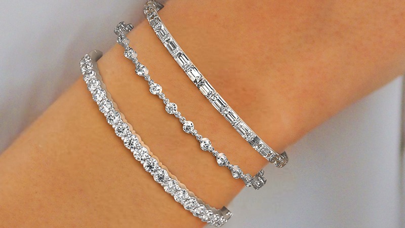 a woman wearing stacked diamond tennis bracelets in different styles