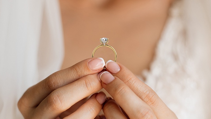 fingers holding a single solitaire Lab grown diamond ring