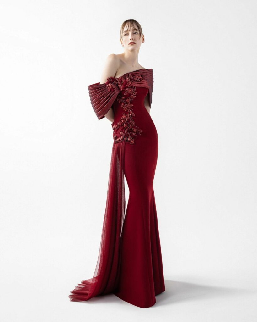 Gaby Charbachy deep wine-red evening dress that blends architectural precision with romantic, organic detailing. It has a sleek, body-hugging silhouette